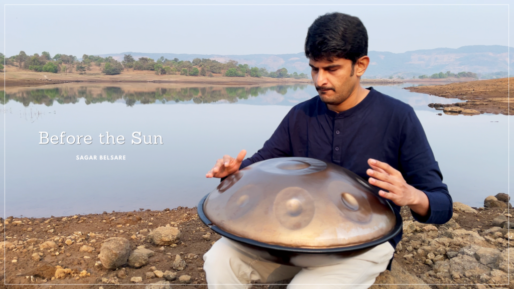Before the Sun handpan performance by Sagar Belsare with title text overlay near a lake