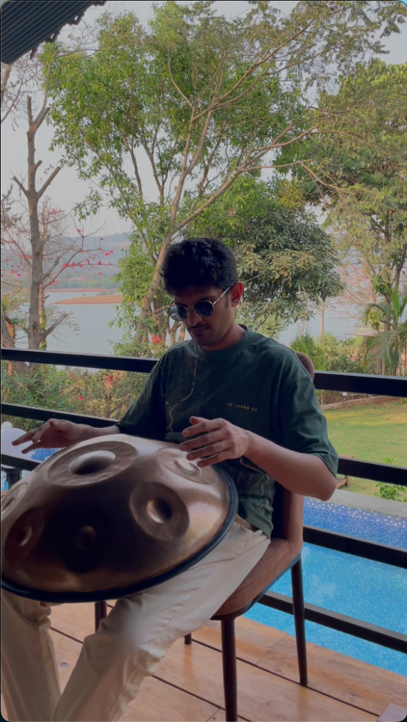 Sagar Belsare performing handpan music at a peaceful lakeside resort setting