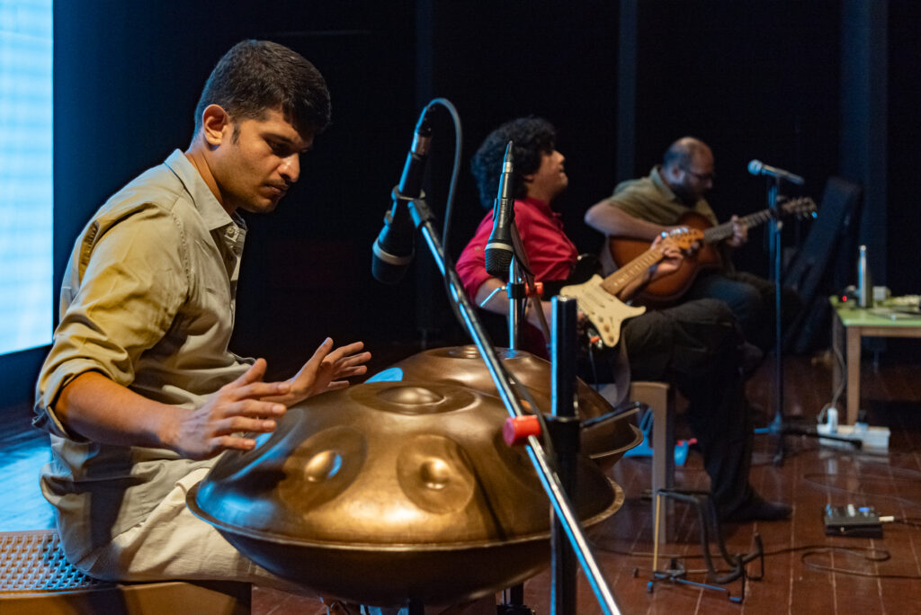 Handpan, acoustic guitar and electric guitar performing together during an immersive live music experience.
