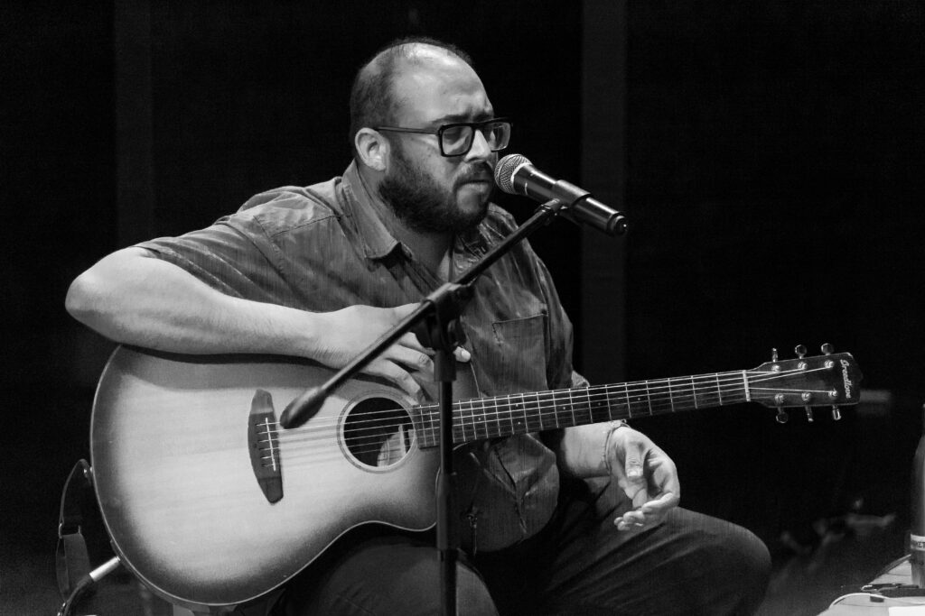 Acoustic guitarist performing live vocals during an immersive music event.